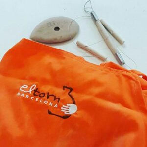 Delantal naranja para hacer cerámica junto a otras herramientas