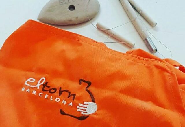 Delantal naranja para hacer cerámica junto a otras herramientas