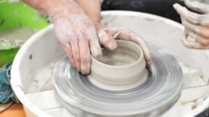 Una persona crea una vasija en el torno de alfarero mientras explora la cerámica artística contemporánea