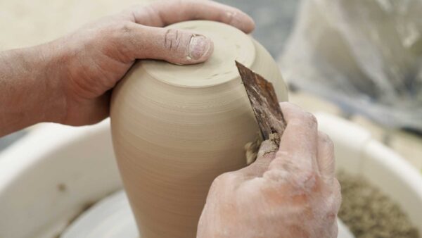 Un artista de la cerámica tornea una pieza en un torno alfarero