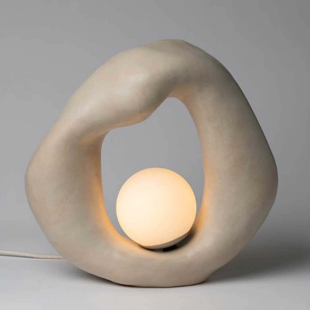 Moderna lámpara de forma orgánica con una base escultórica y una esfera luminosa central que emite una luz suave y envolvente