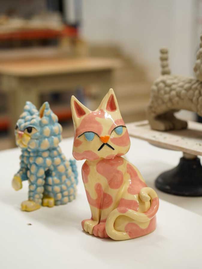 Esculturas de gatos pintados de varios colores sobre una mesa