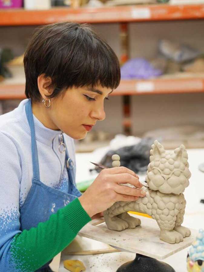 Una mujer ceramista hace una figura decorativa de un gato
